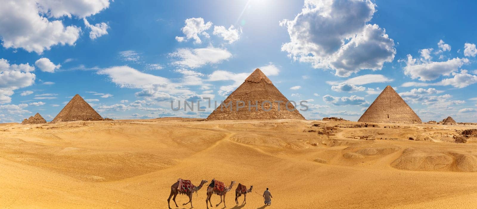 Panorama of Giza with the Pyramids, camels and a bedouin.