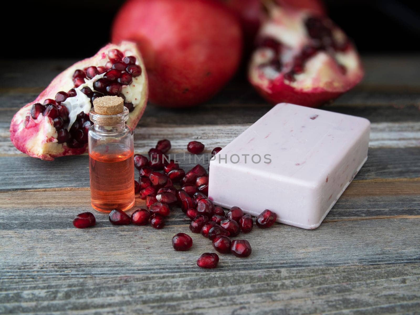 Pomegranate extract soap with a small bottle of extrace and pieces of a pomegranate.