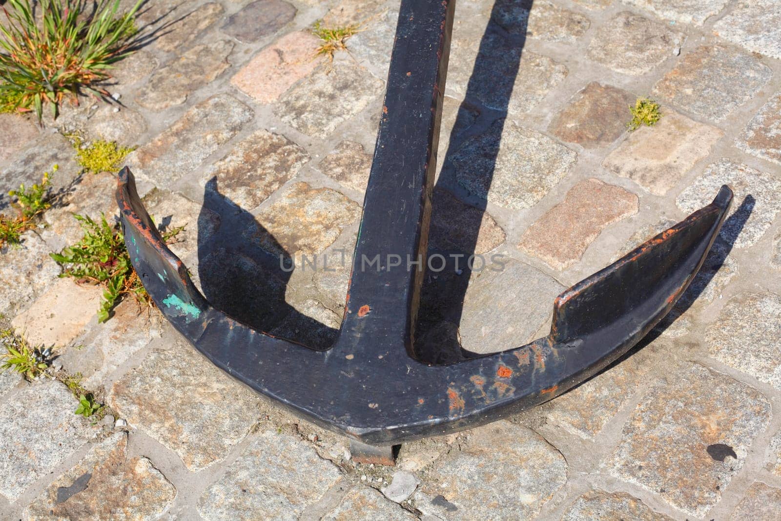 Black iron anchor, lying on the ground