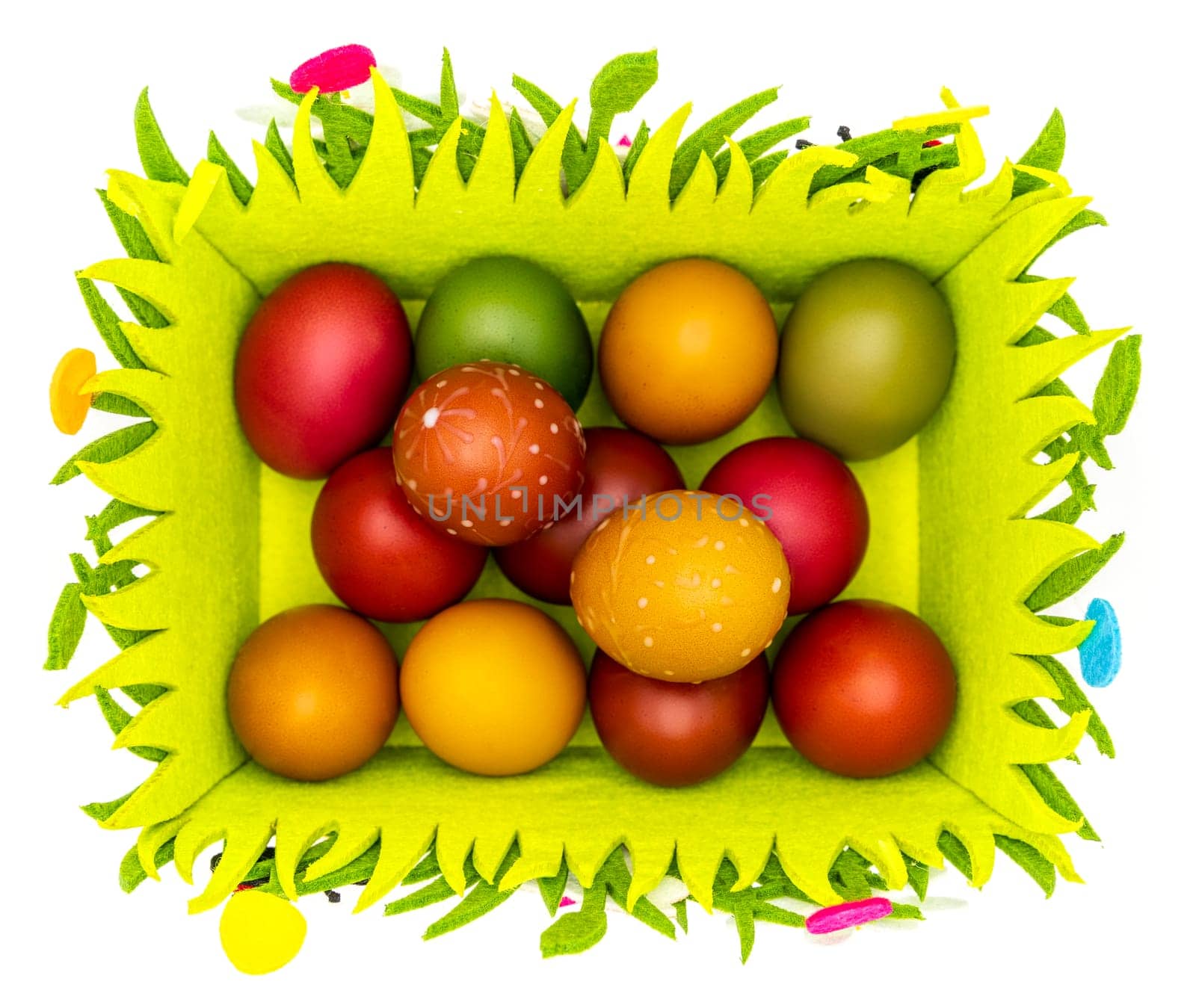 Stash of colorful Easter eggs, wax painted in a felt Easter basket on plain white background, isolated, top view