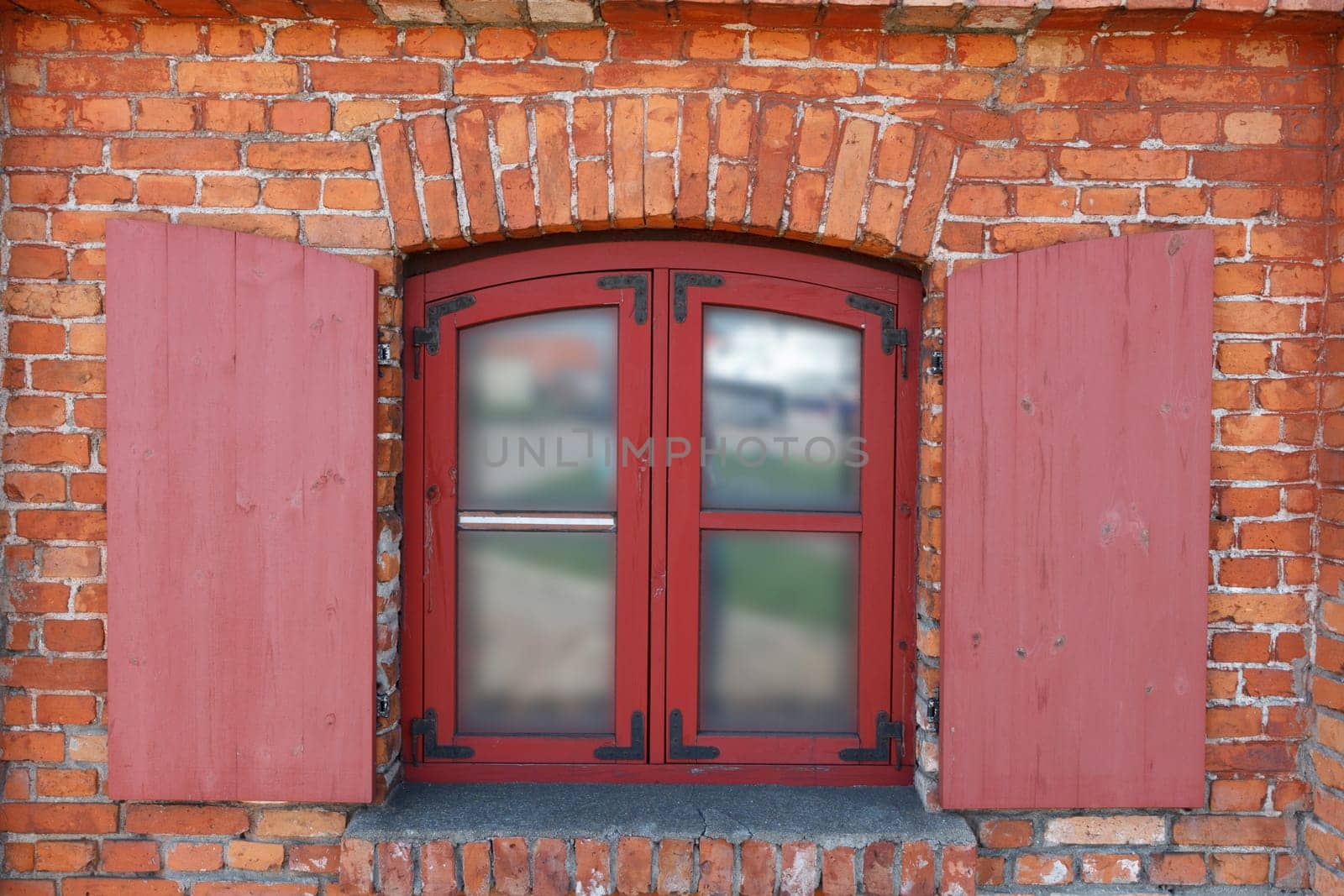 Classic wooden window with shutters on red brick wall
