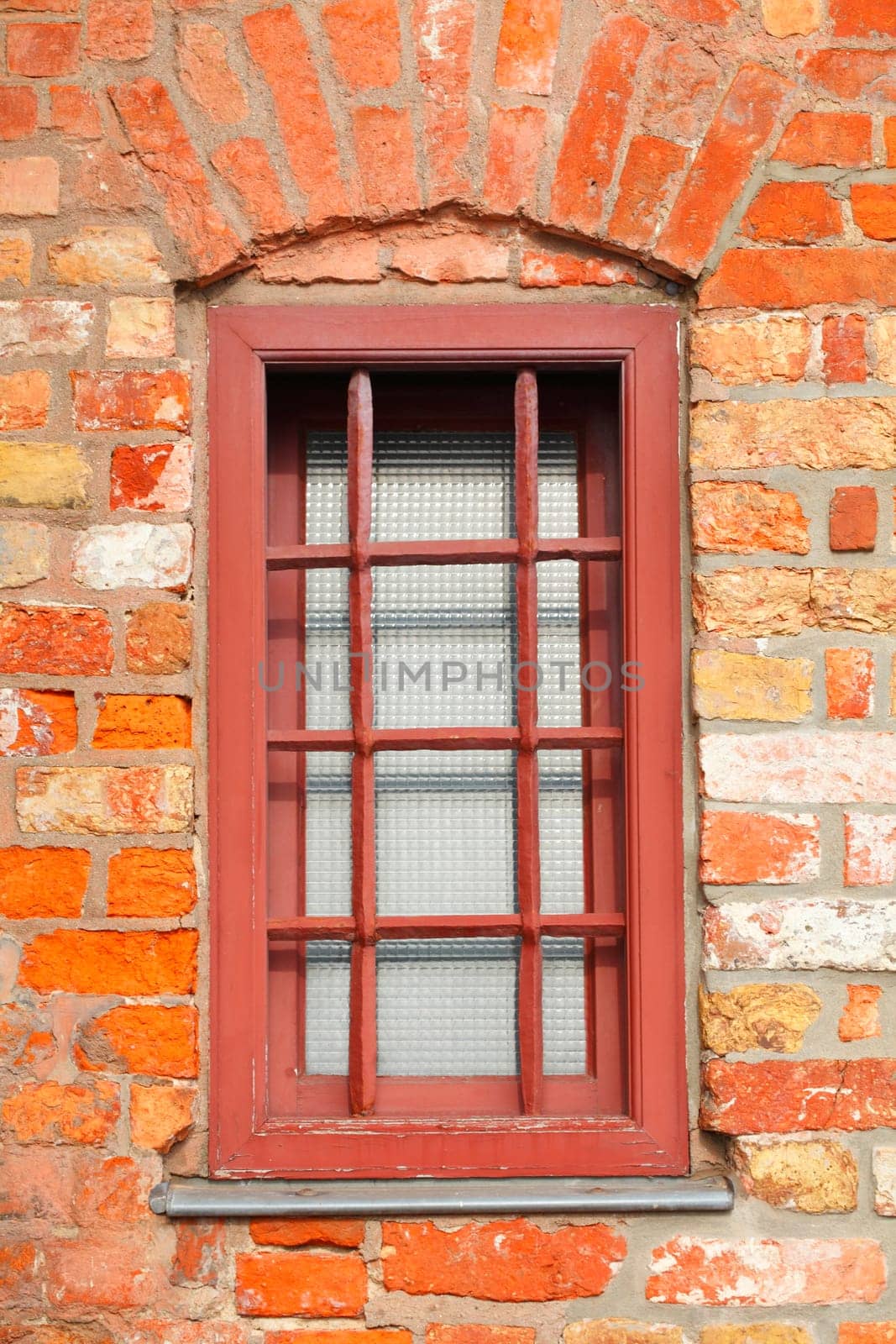 Old window with brick house wall and window bars