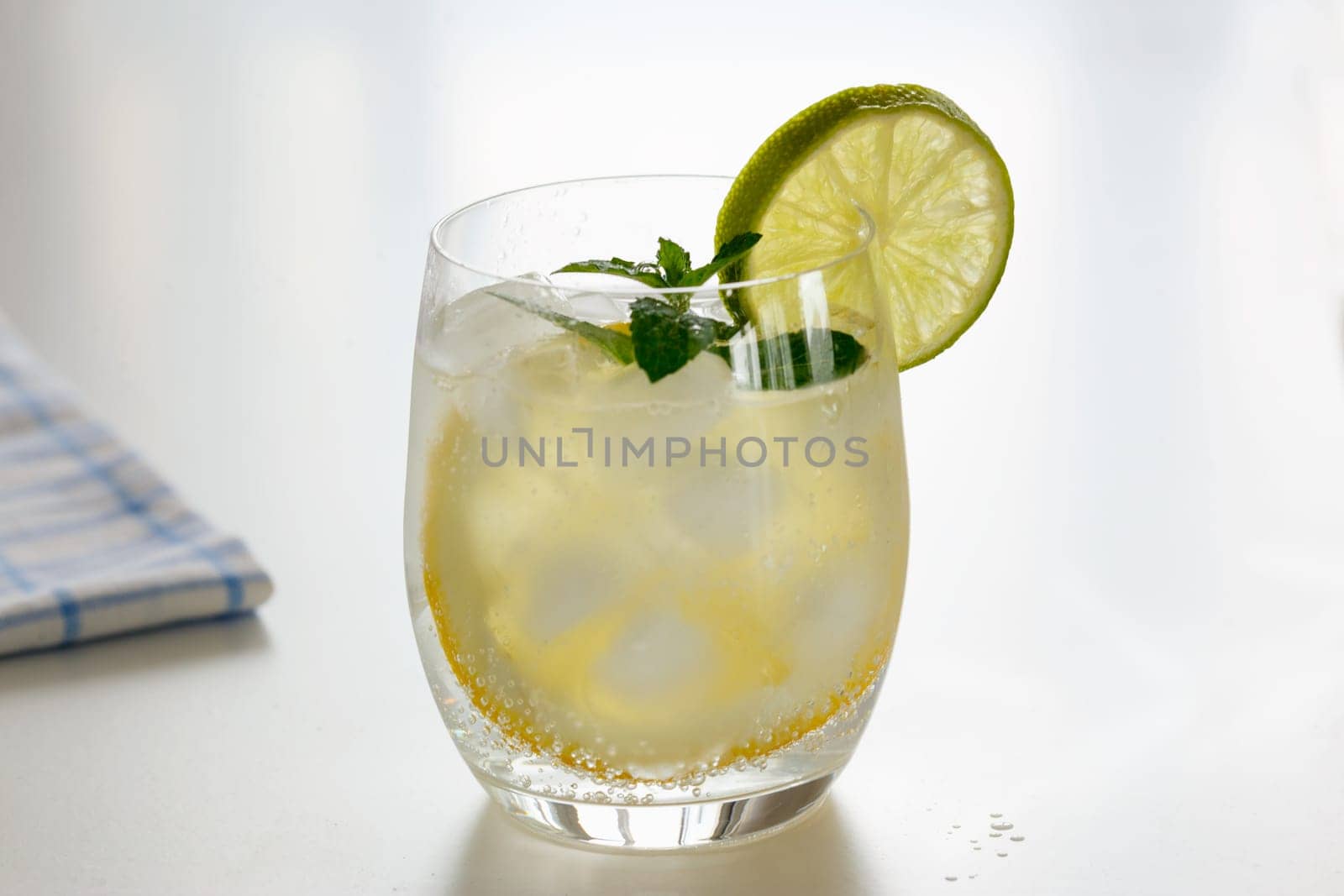 Mineral water with lemon in a steaming glass with slices of lemon, lime and a sprig of mint