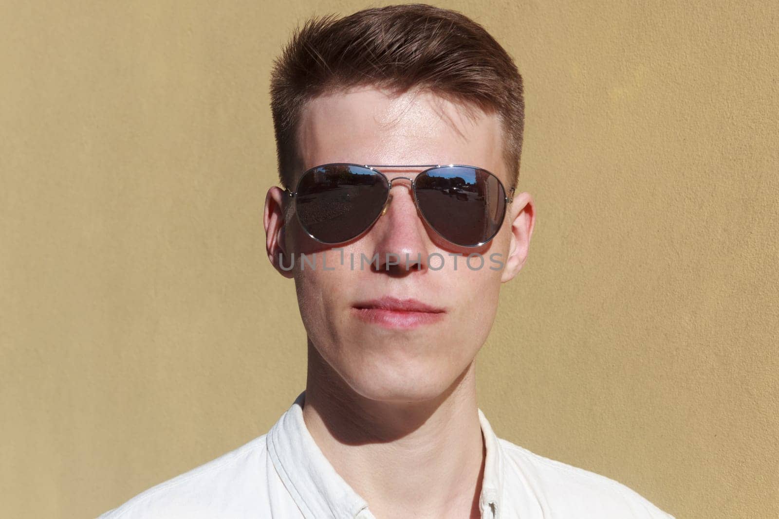 portrait of a handsome man dressed in white shirt against yellow wall