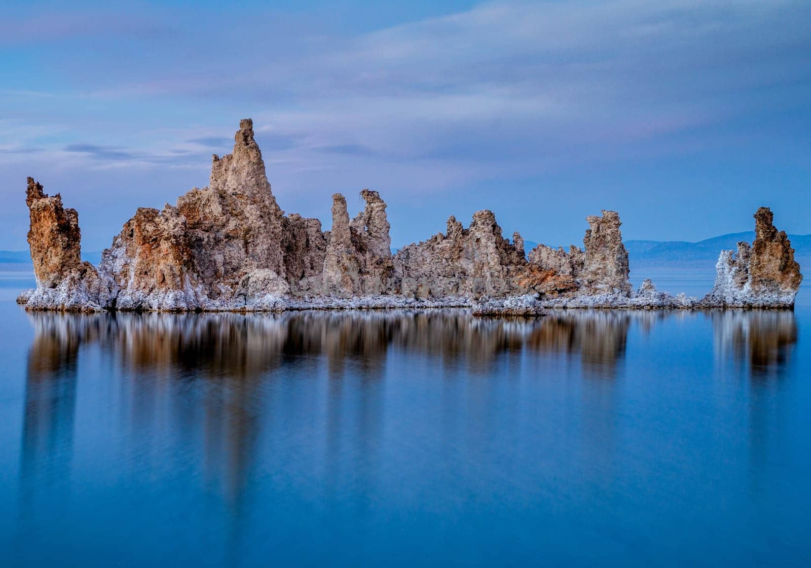 Ancient lake in a crater of an extinct volcano. Tufa stalactites are reflected in smooth water of lake