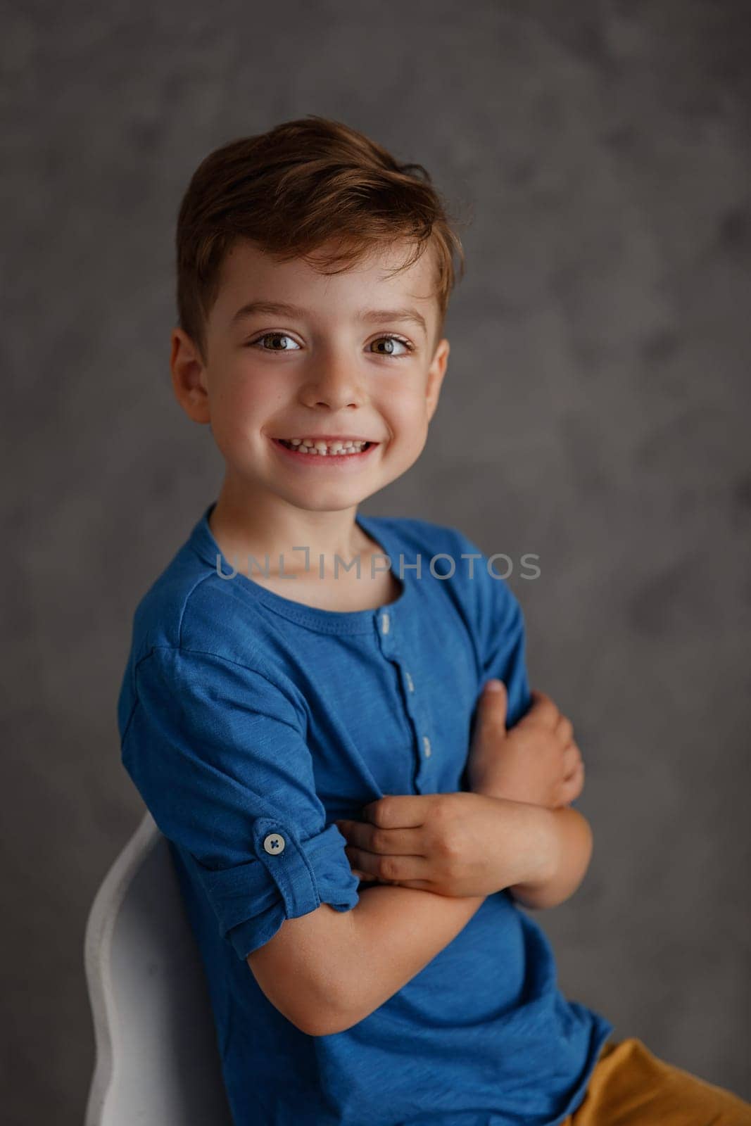5 year old boy blue shirt and yellow pants studio portrait on gray background.