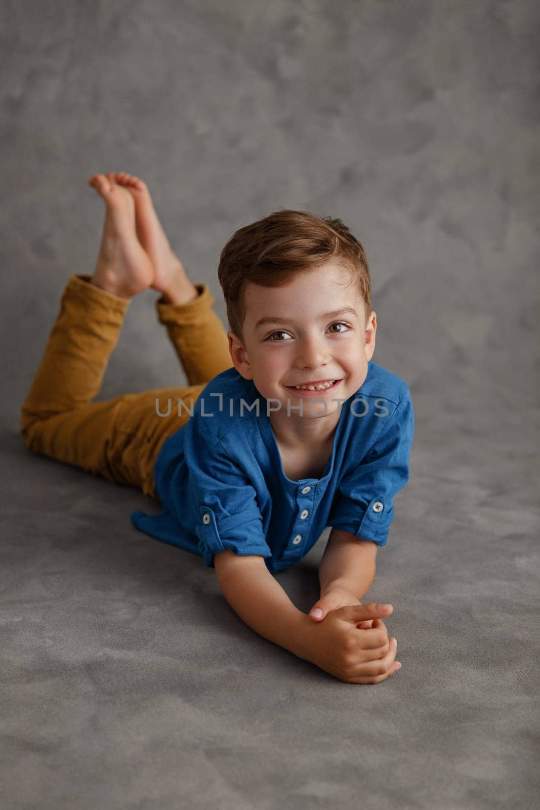 5 year old boy blue shirt and yellow pants studio portrait on gray background.