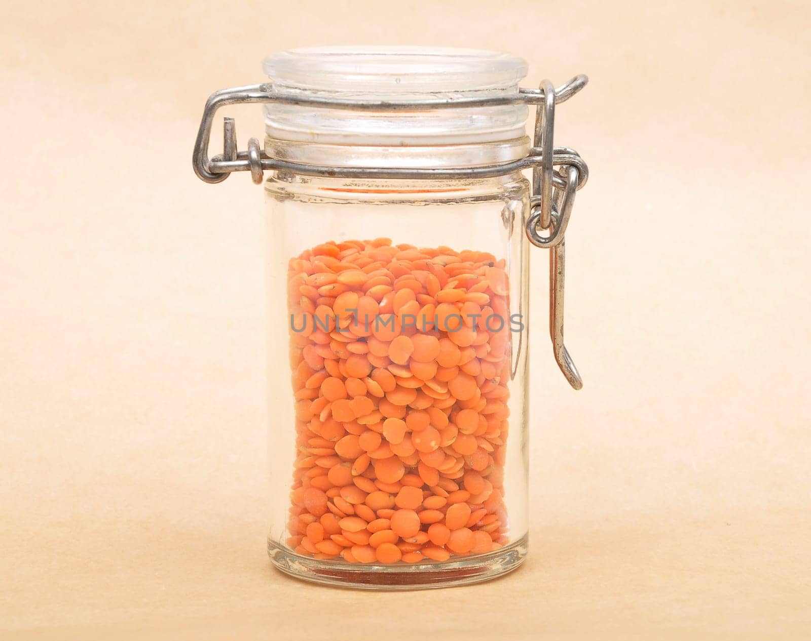 Red lentils in jar and brown background