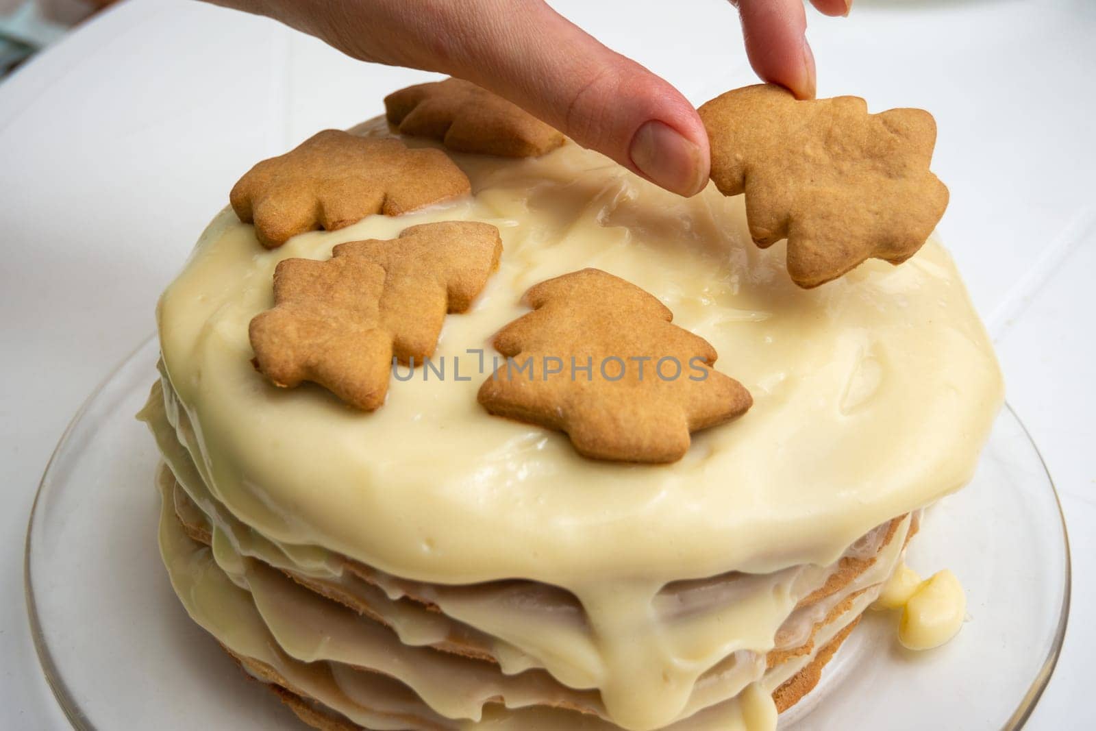 Homemade cake with condensed milk, a hand on top puts a Christmas tree cookie