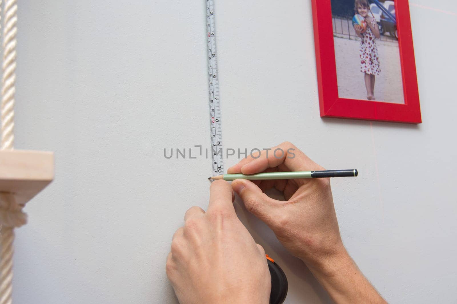 Hands mark out on the wall the arrangement of frames with photos
