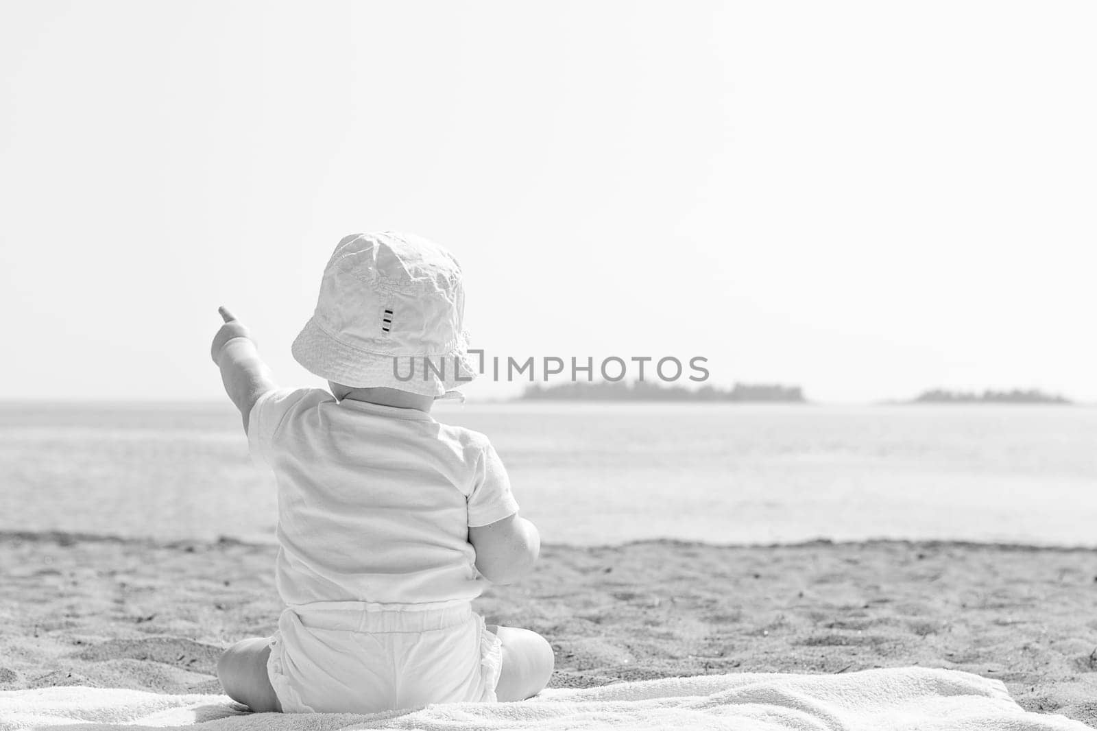 Baby Pointing to the Sky by Ocean in black and white.