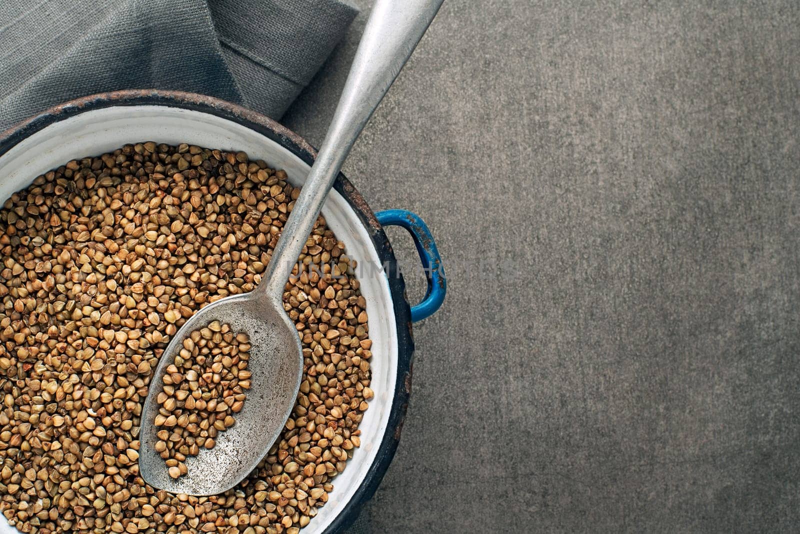 Dry buckwheat cereal grains with spoon close up.