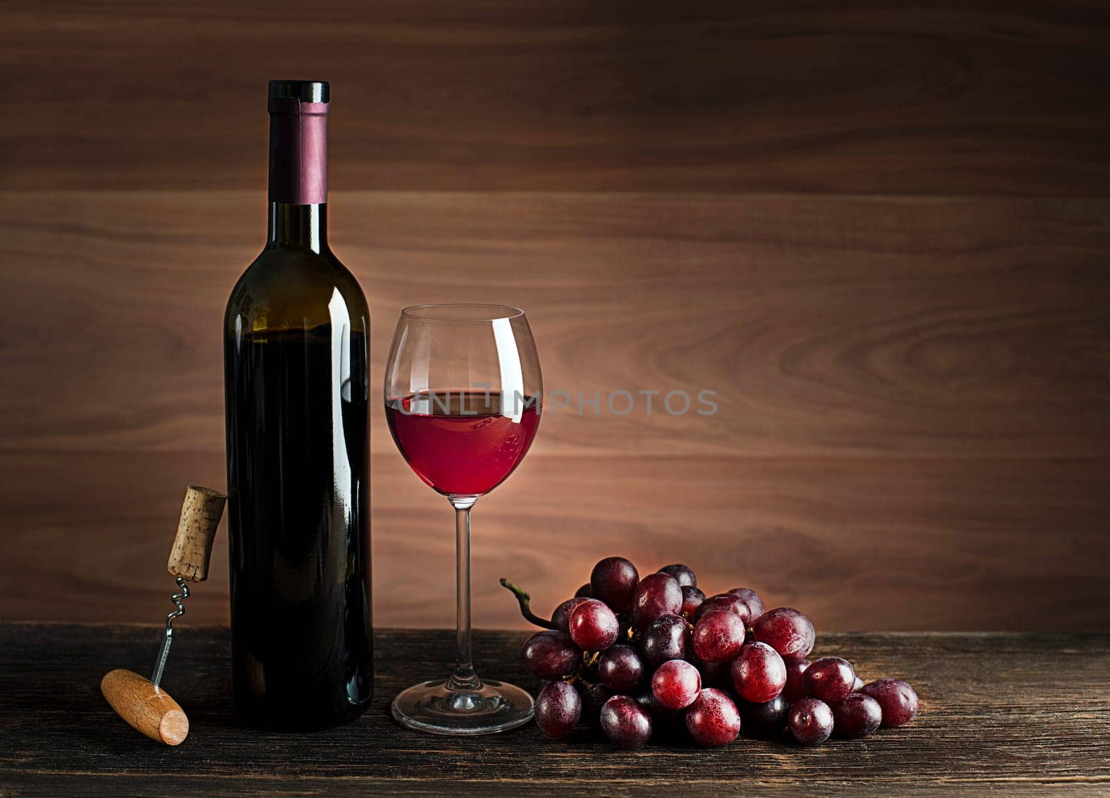 Glass and bottle of red wine on wooden background