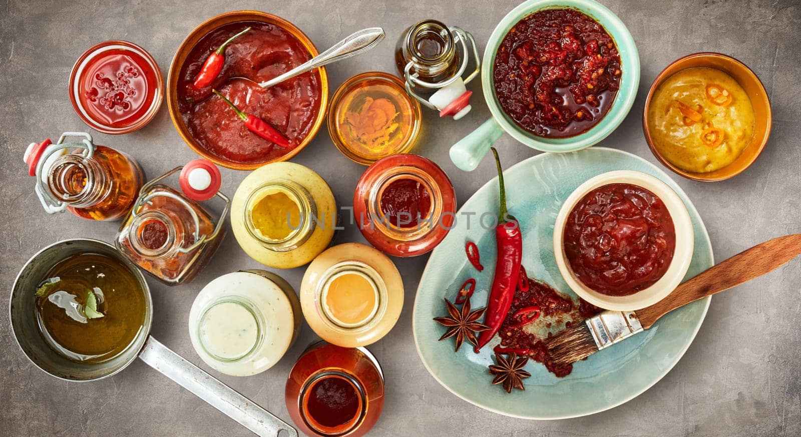 Overhead view of assorted savory, hot spicy and piquant sauces and marinades in bowls and bottles for a summer BBQ in a panorama banner