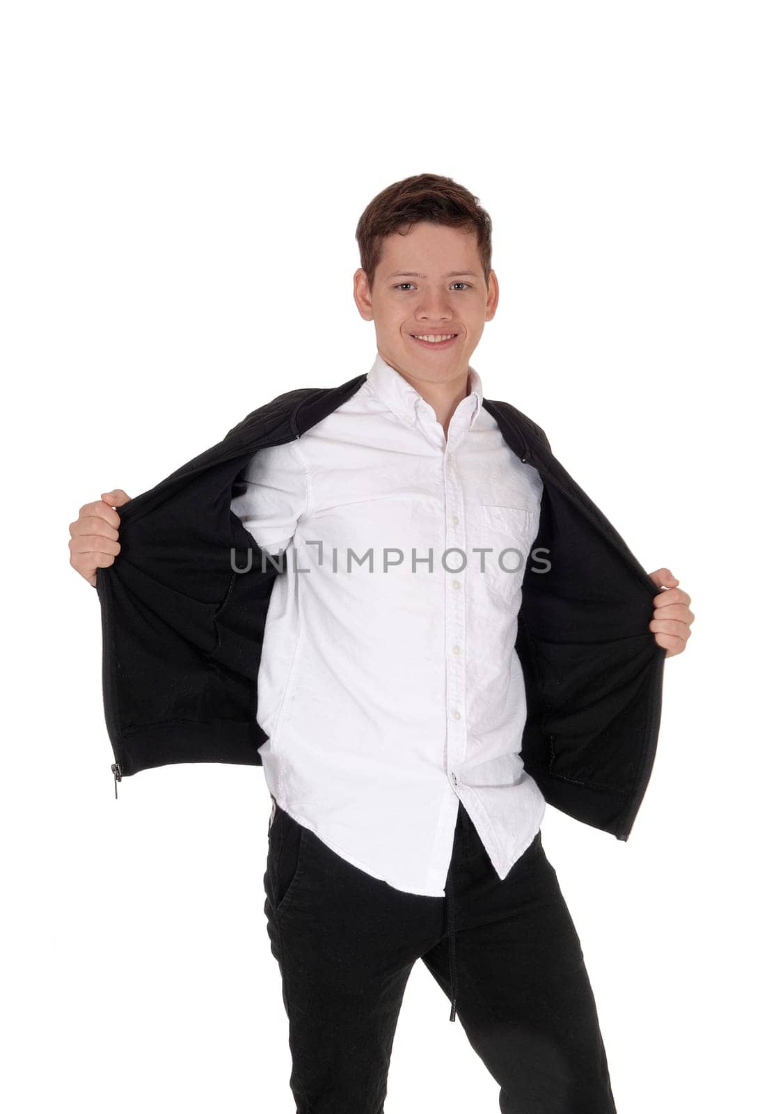A lovely young teenager boy standing in the studio, smiling, holding.his black jacket open, whit a white shirt, isolated for white background.