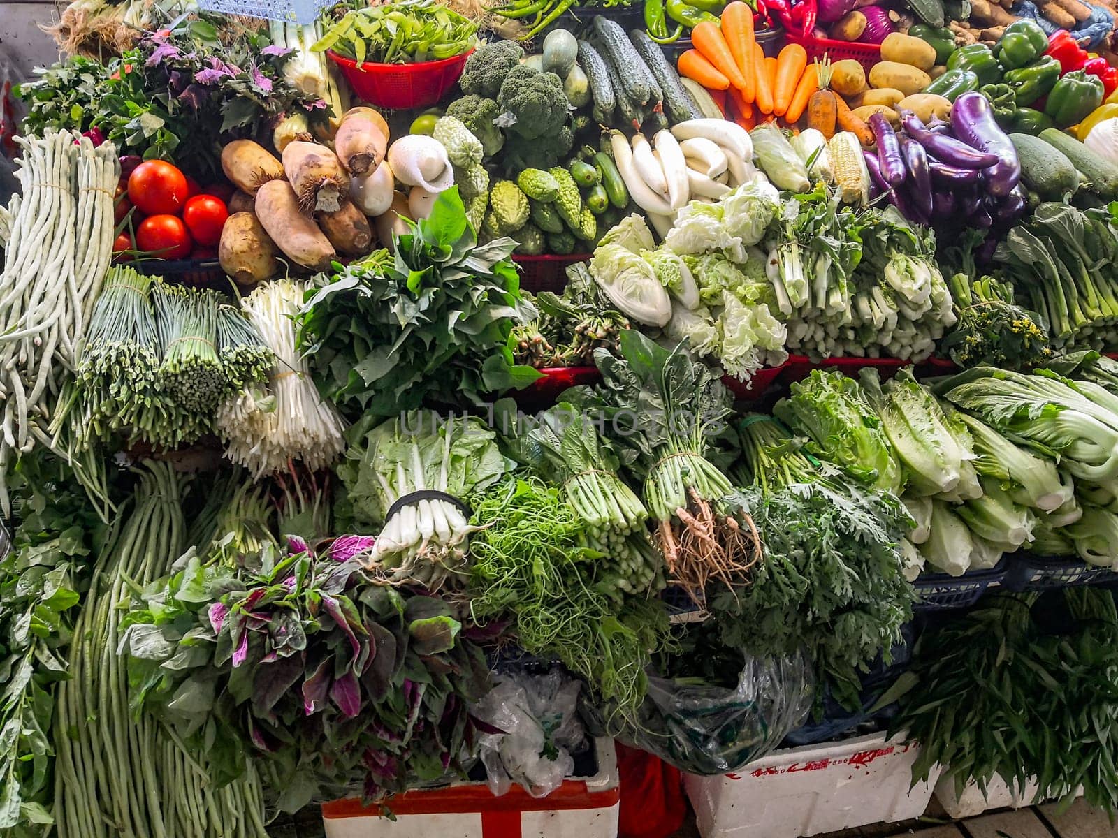 A counter with fresh vegetables in a Chinese market, farm products, greens and vegetables