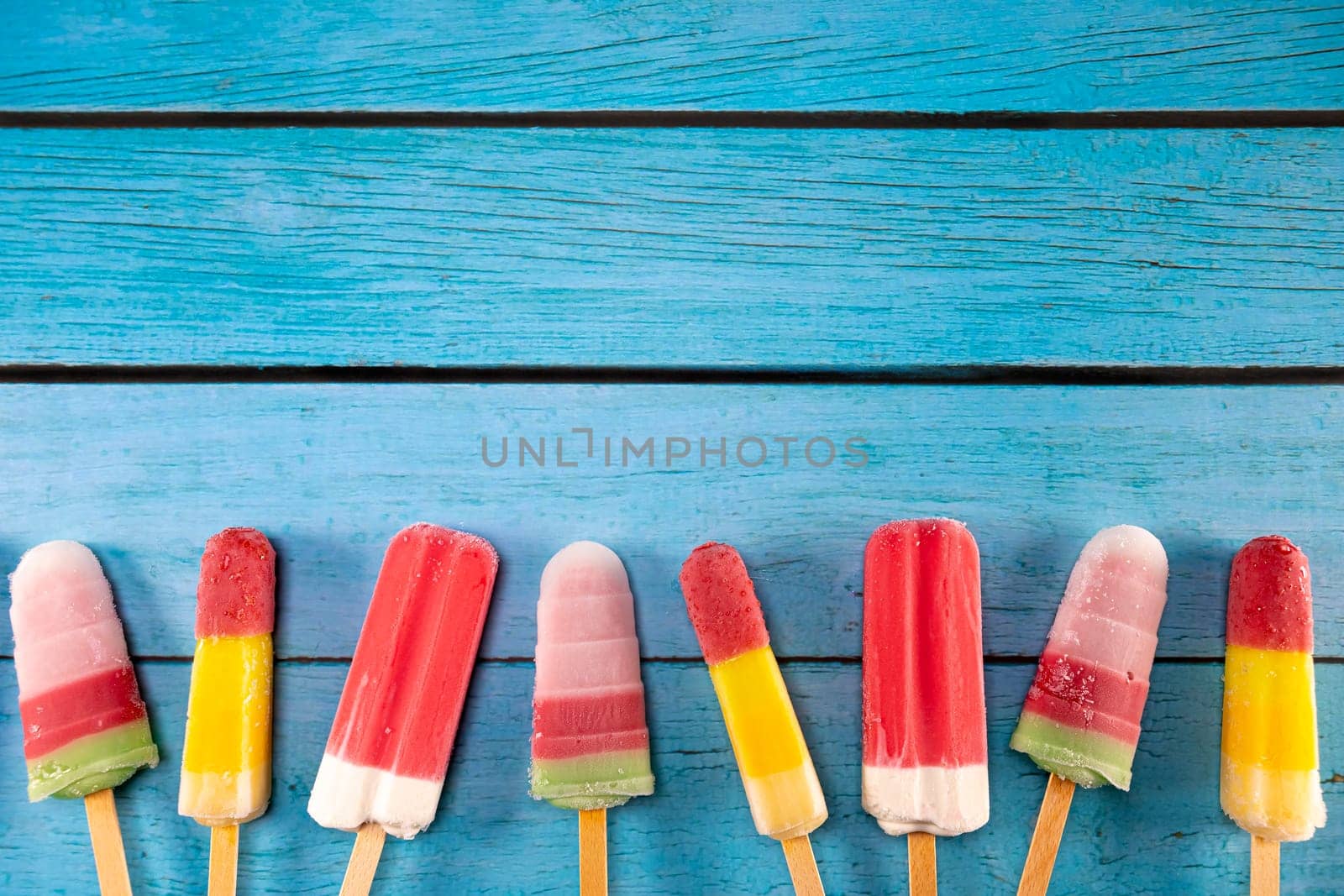 Colorful fruit ice cream stick look fresh to eat placed on a blue vintage wooden. Focus on ice crean sticks.