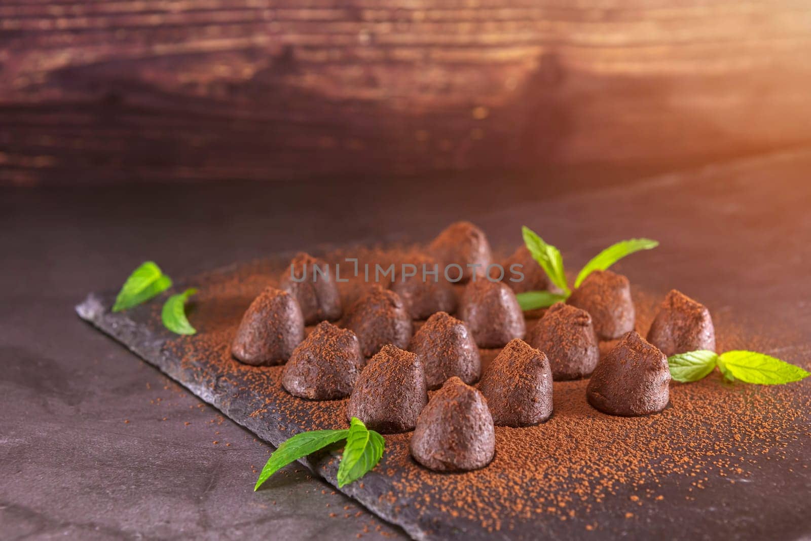 Homemade chocolate truffles with mint sprinkled with cocoa powder on slate. Focus on truffles