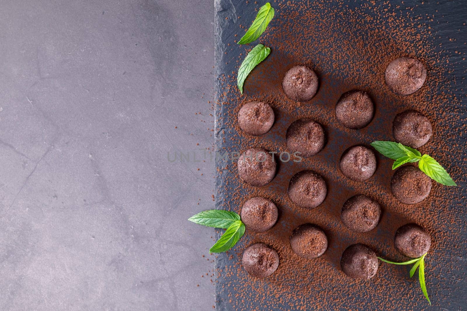 Top view of delicious chocolate truffles powdered with cocoa on slate. Focus on truffles.