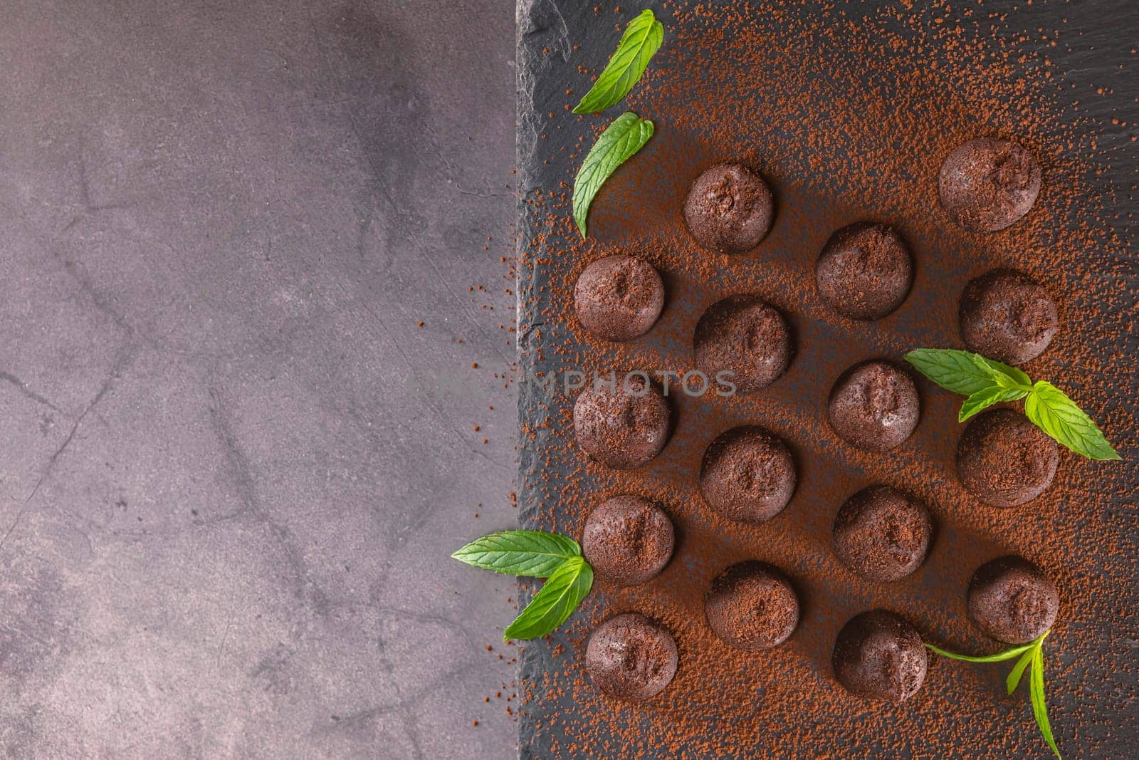 Top view of delicious chocolate truffles powdered with cocoa on slate.
