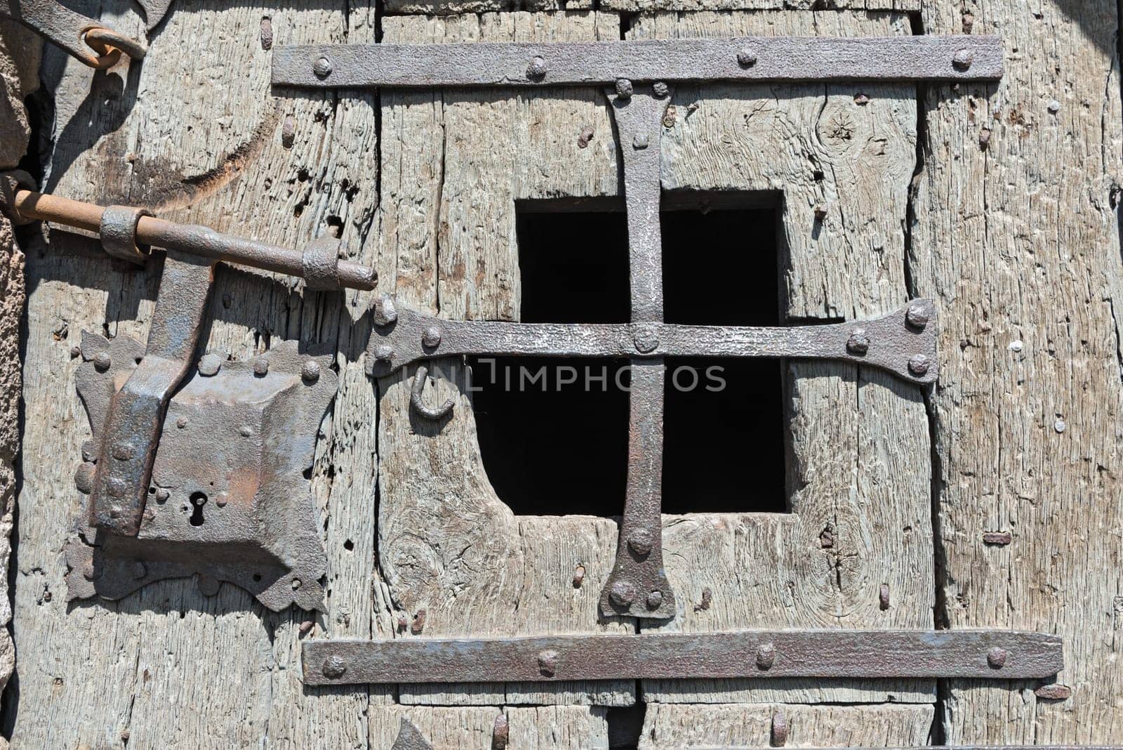 Old medieval wooden door with window and wrought iron fittings