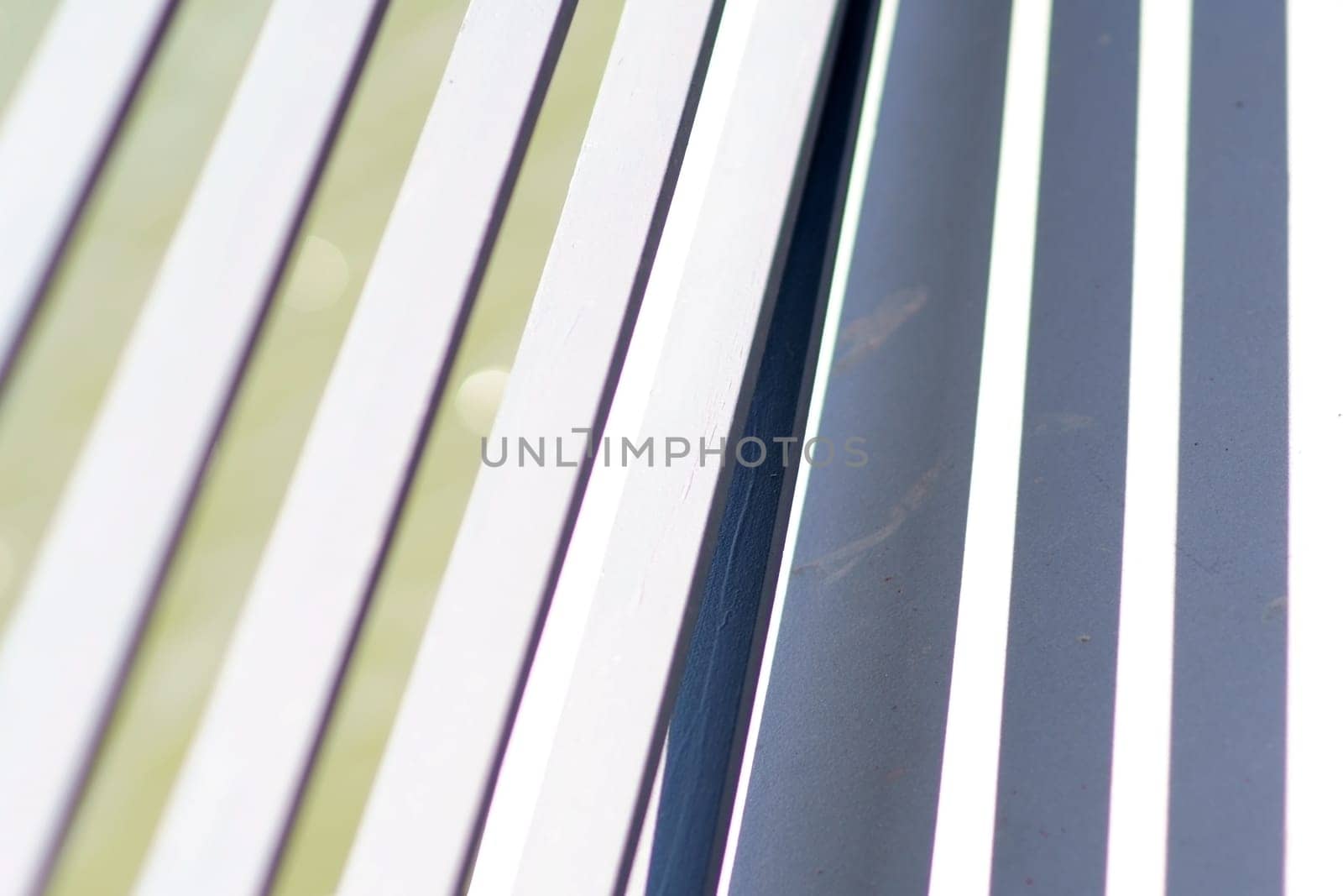 The close-up of the white-painted crossbars of a bridge railing, which casts symmetrical shadows.
