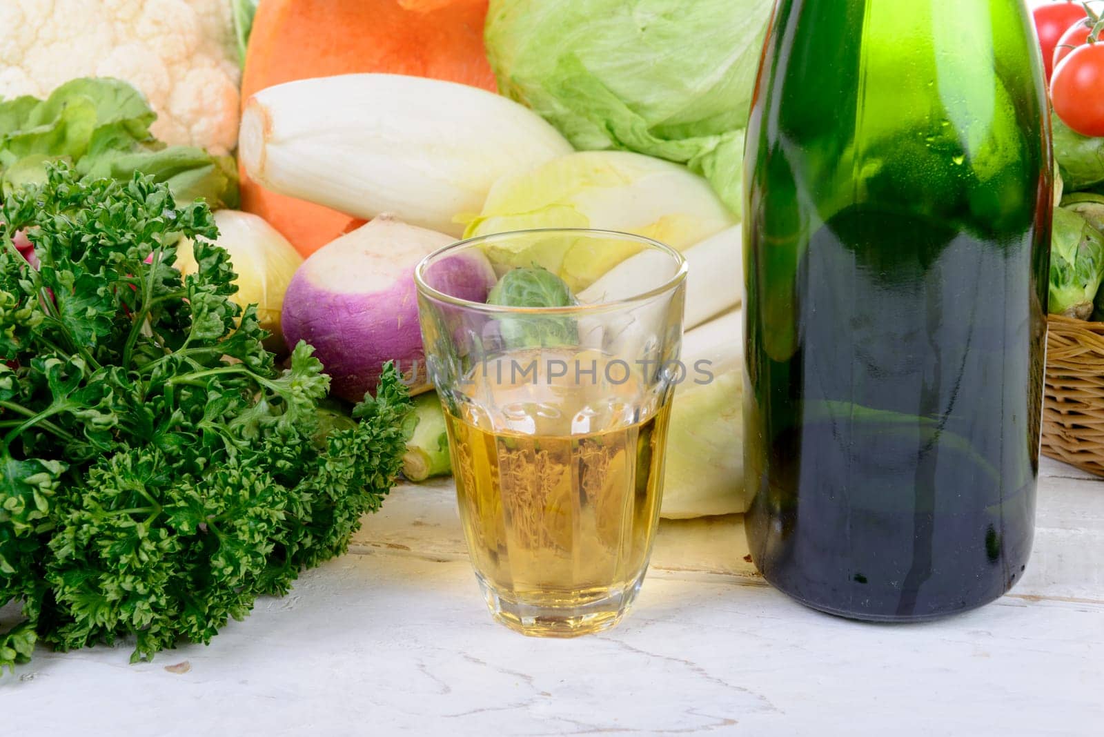 Glass and bottle of cider with vegetables on table