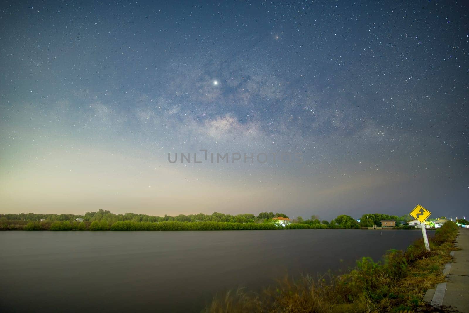 Signs, signs, beware of curves at night, behind the sign, with the Milky Way..