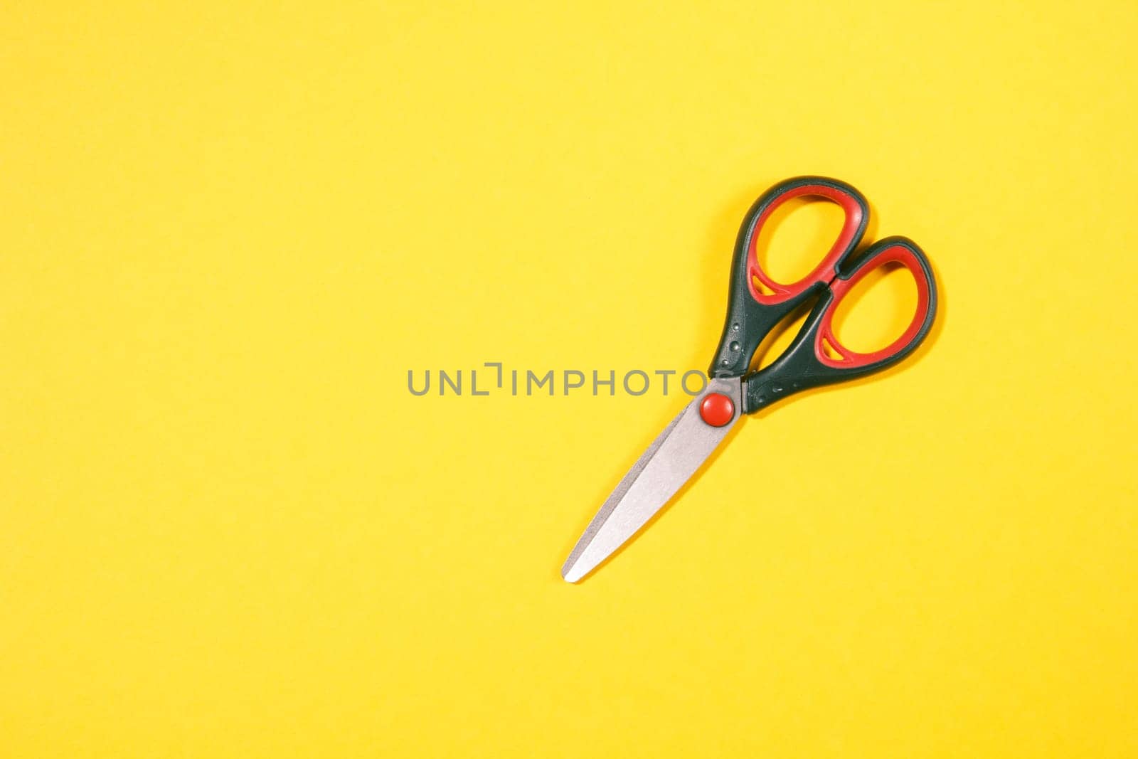 closed black scissors with red elements on yellow background
