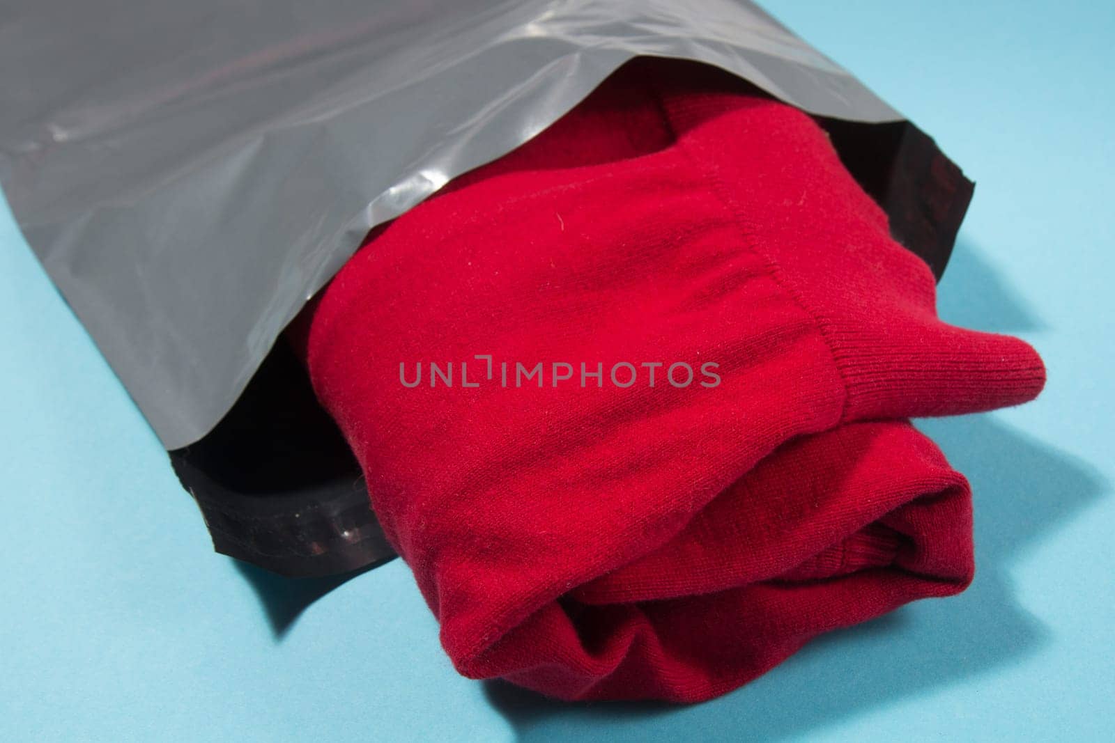 red jumper packed in gray mailing bag