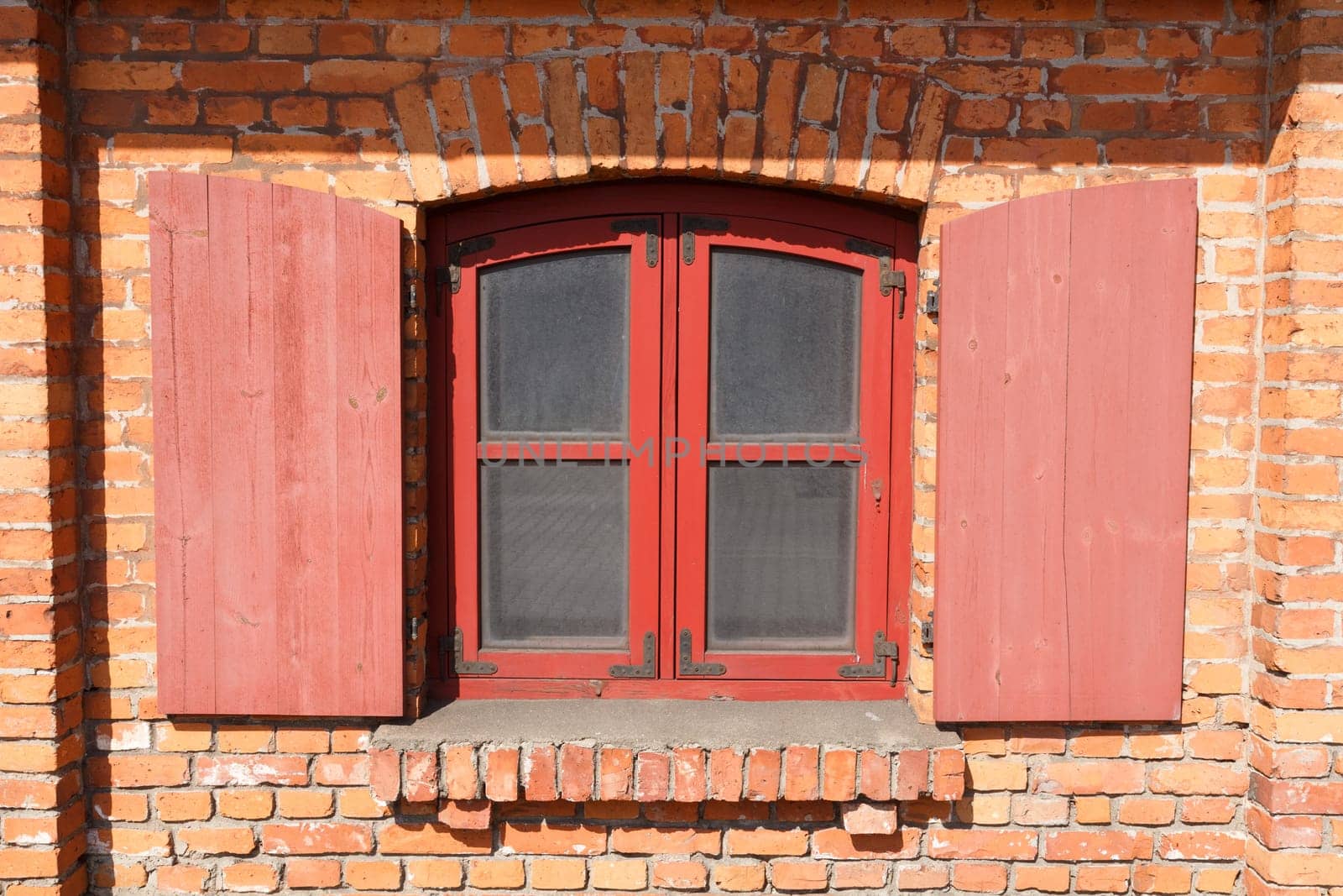Classic wooden window with shutters on red brick wall