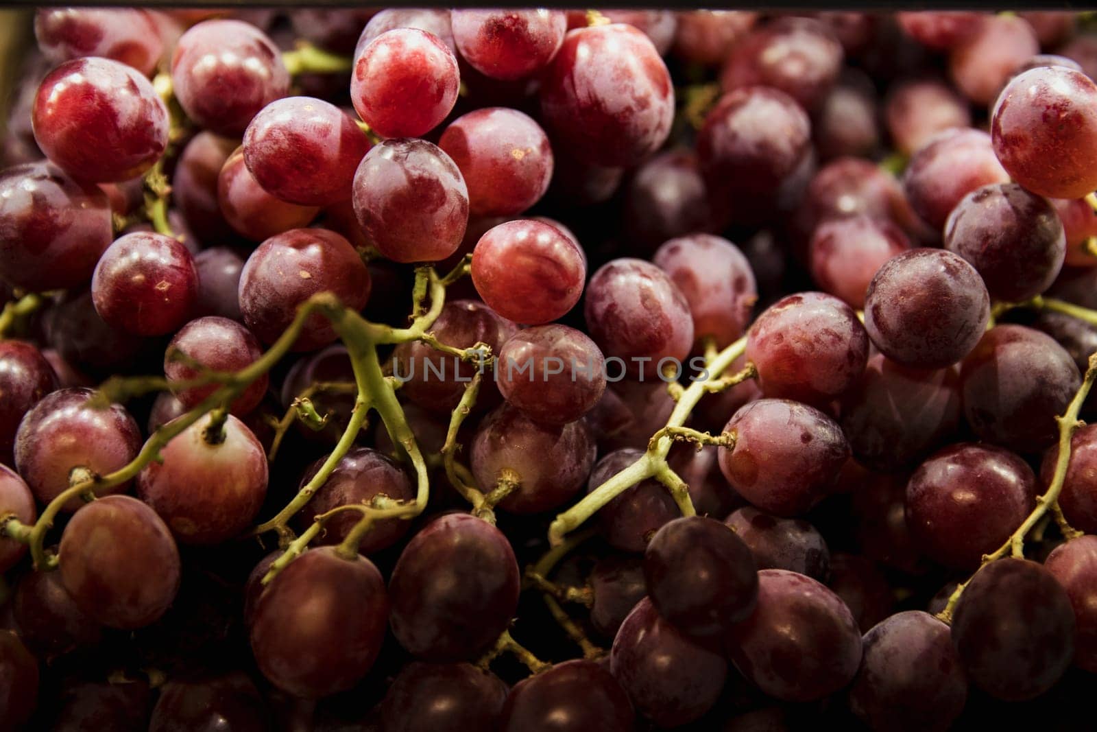A close-up shot of an abundance of fresh Red Grapes on display at a market stall.