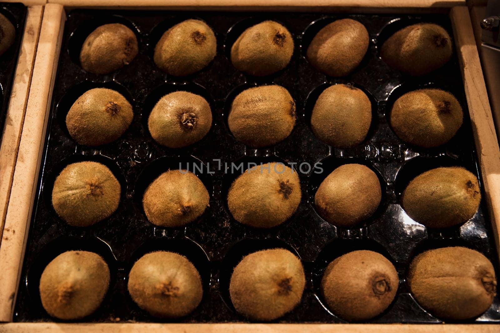 A close-up shot of an abundance of fresh Kiwi on display at a market stall.