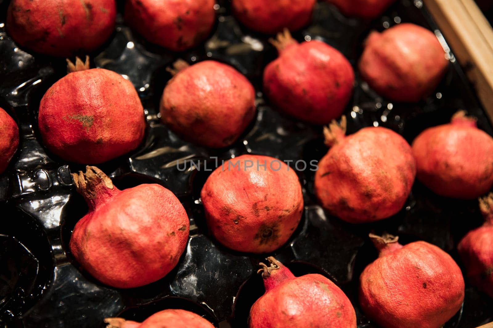 A close-up shot of an abundance of fresh Pomegranate on display at a market stall.