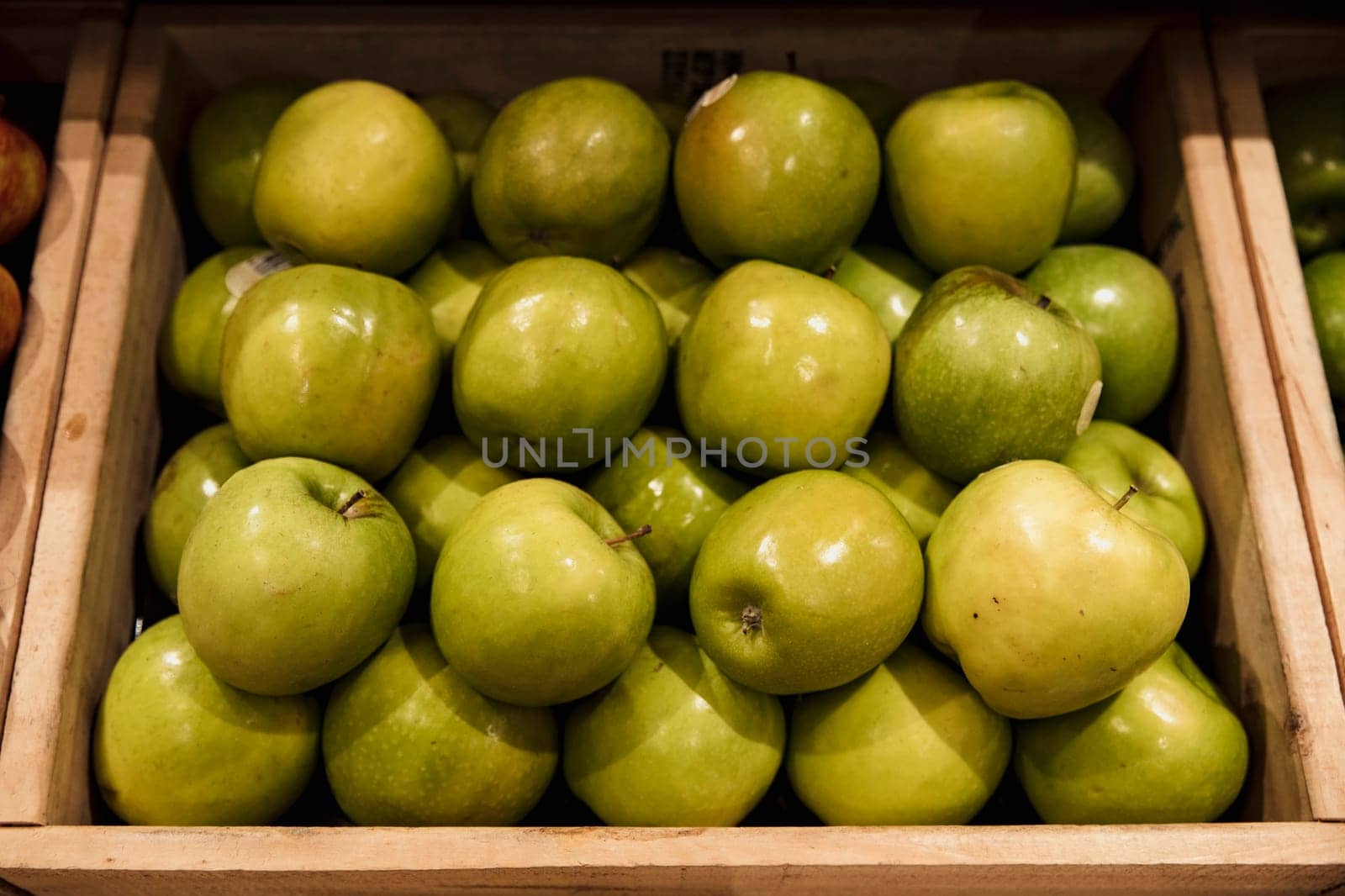 A close-up shot of an abundance of fresh Green Apples on display at a market stall.