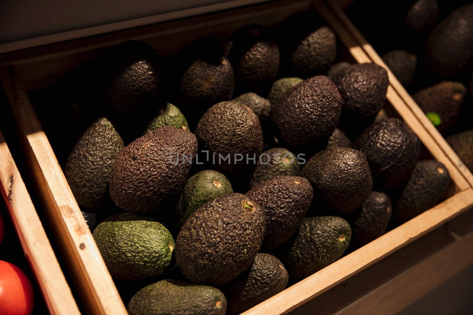 A close-up shot of an abundance of fresh Avocado's on display at a market stall.