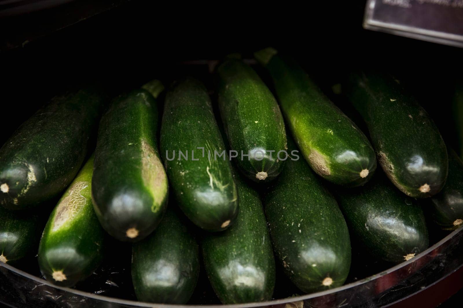 A close-up shot of an abundance of fresh courgette's on display at a market stall.