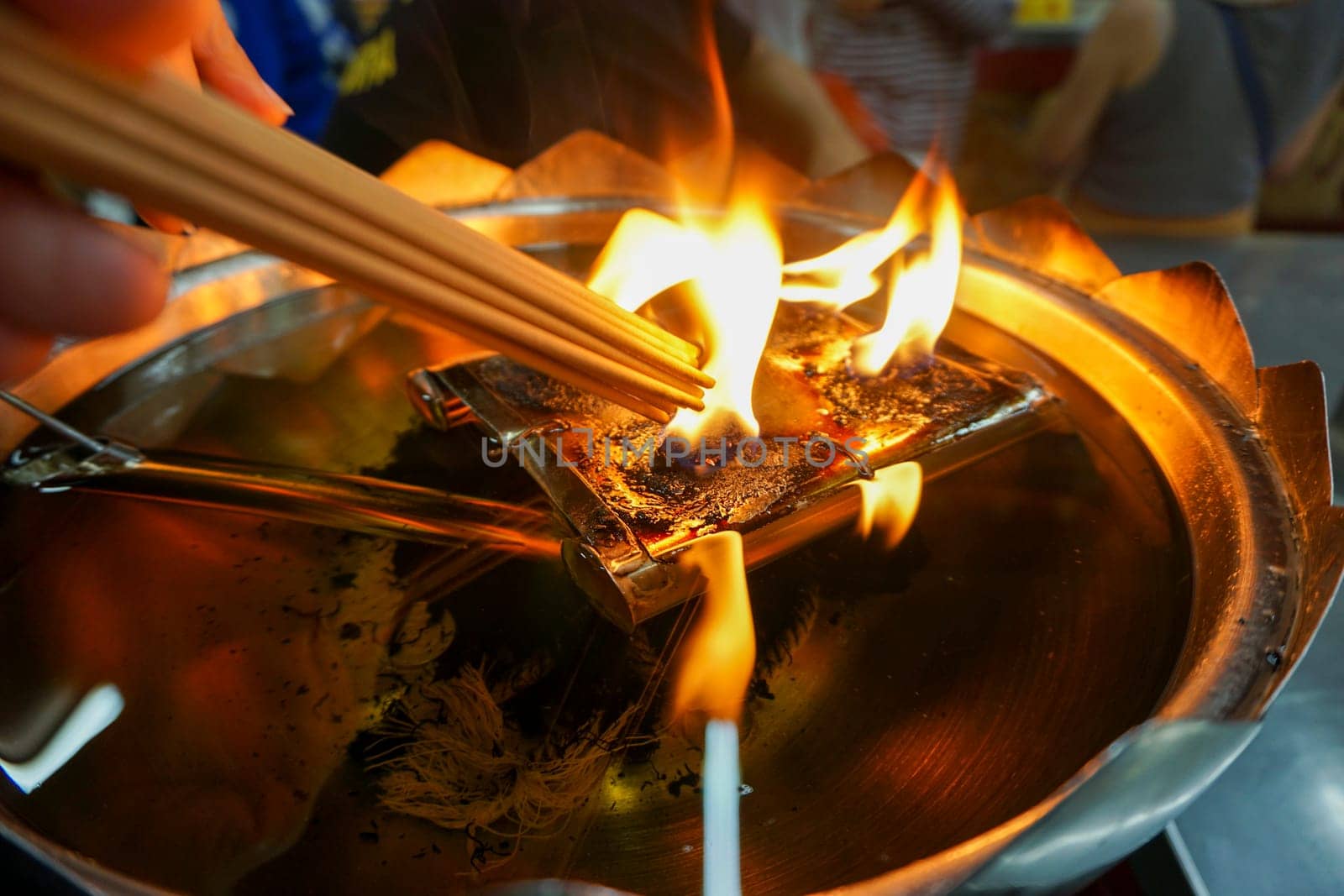Incense is being lit by fire. From a large lamp
