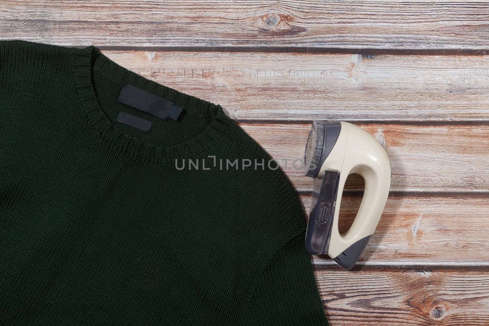 wool sweater with electric lint remover on wooden background