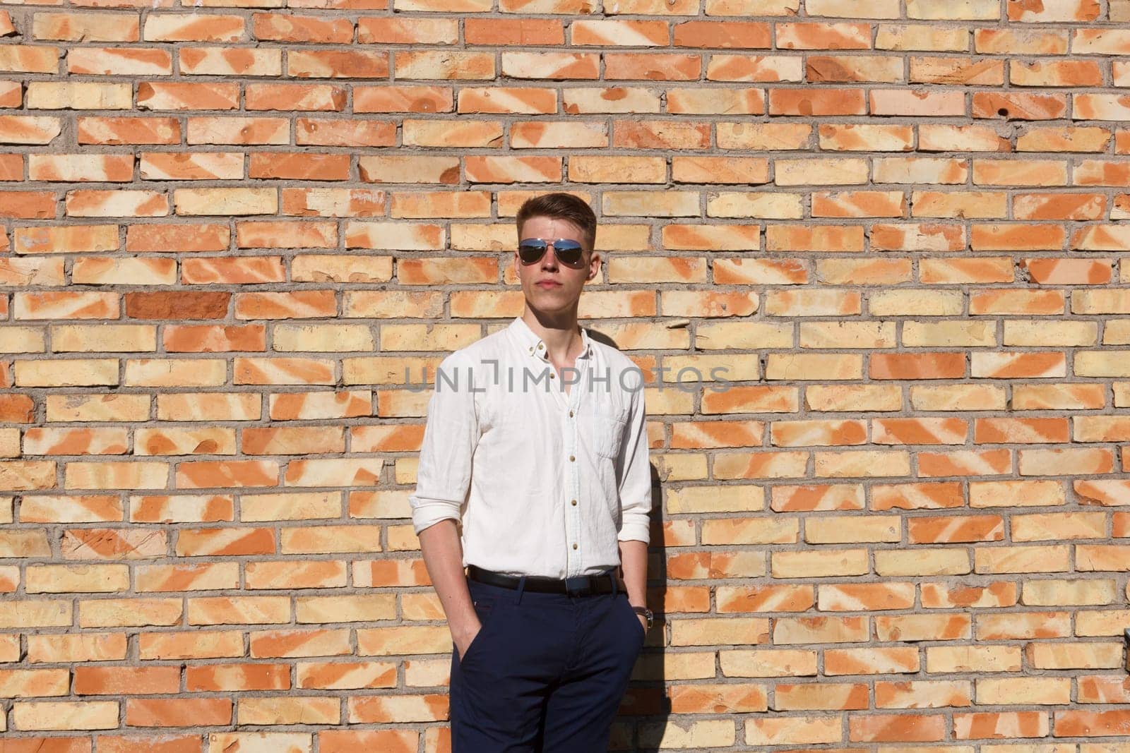 Portrait of a casually dressed young businessman standing against a brick wall