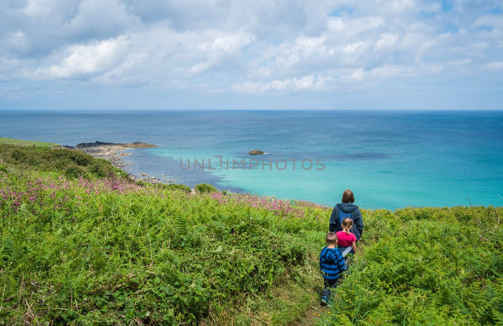 Family walking on a small path along the stunning Cornish coastline near St. Ives in Cornwall, England, UK