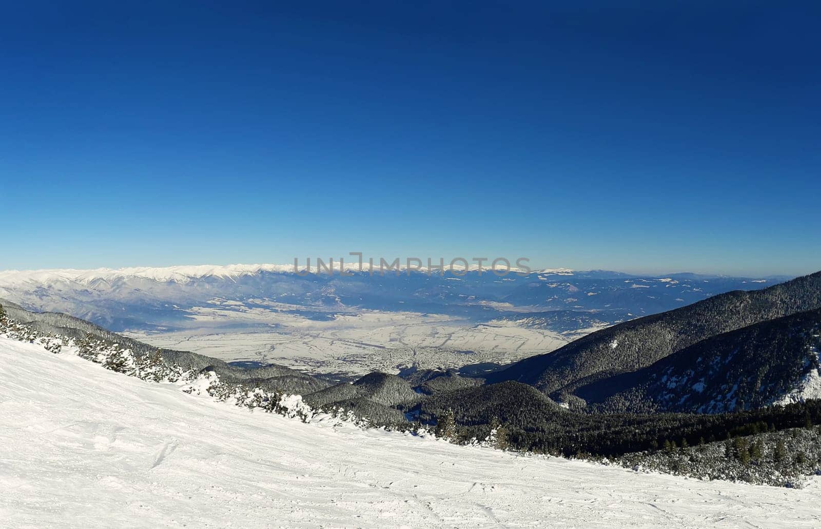 Ski slope and panorama of winter mountains. Alpine ski resort Bansko, Bulgaria