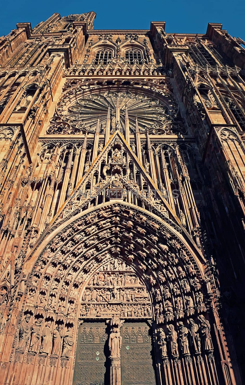 The Gate of Roman Catholic Cathedral Notre Dame of Strasbourg in Alsace, France. Beautiful sunny day with clear blue sky. Majestic gothic architecture.