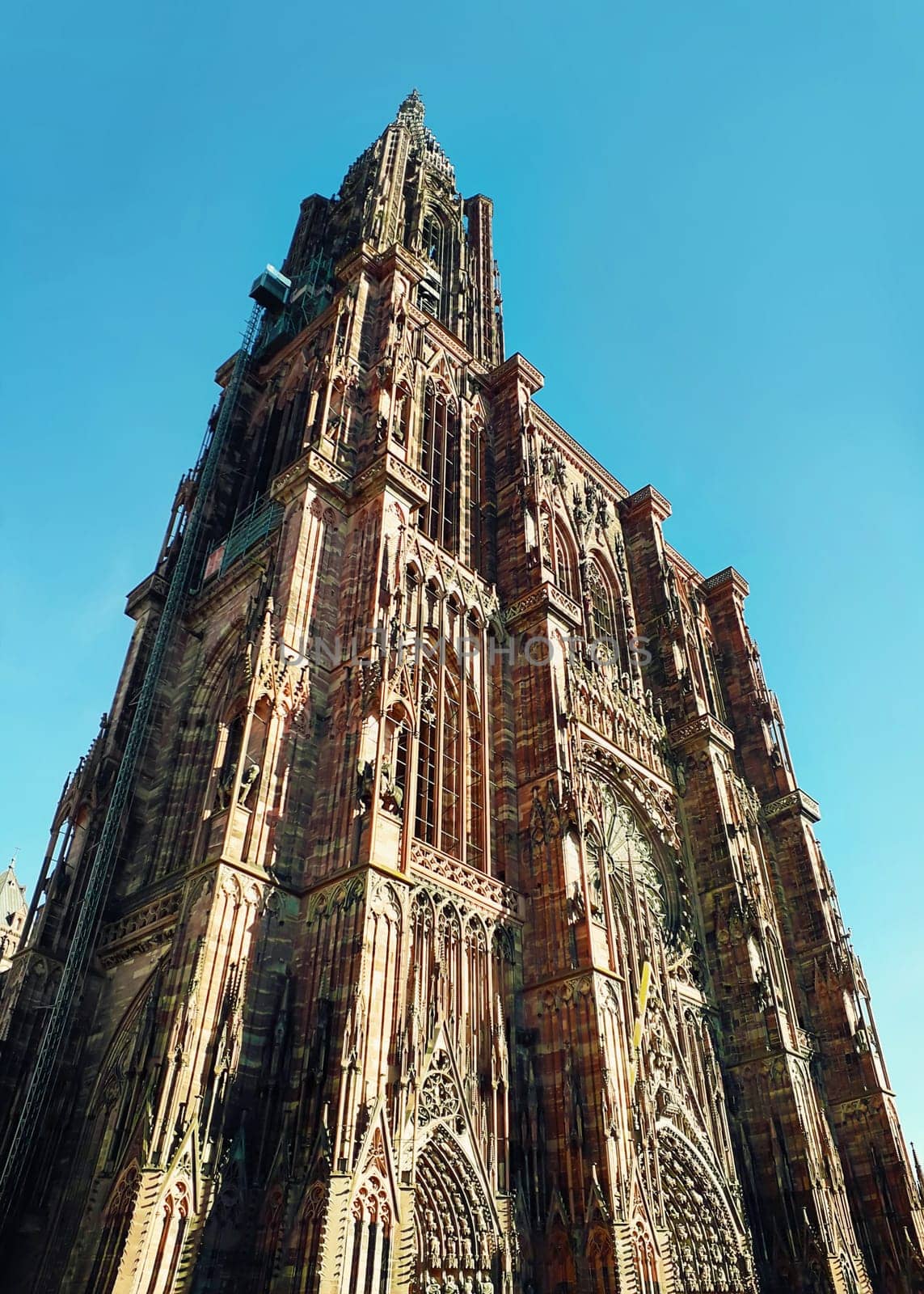 The tower of Roman Catholic Cathedral Notre Dame of Strasbourg in Alsace, France. Beautiful sunny day with clear blue sky. Majestic gothic architecture.
