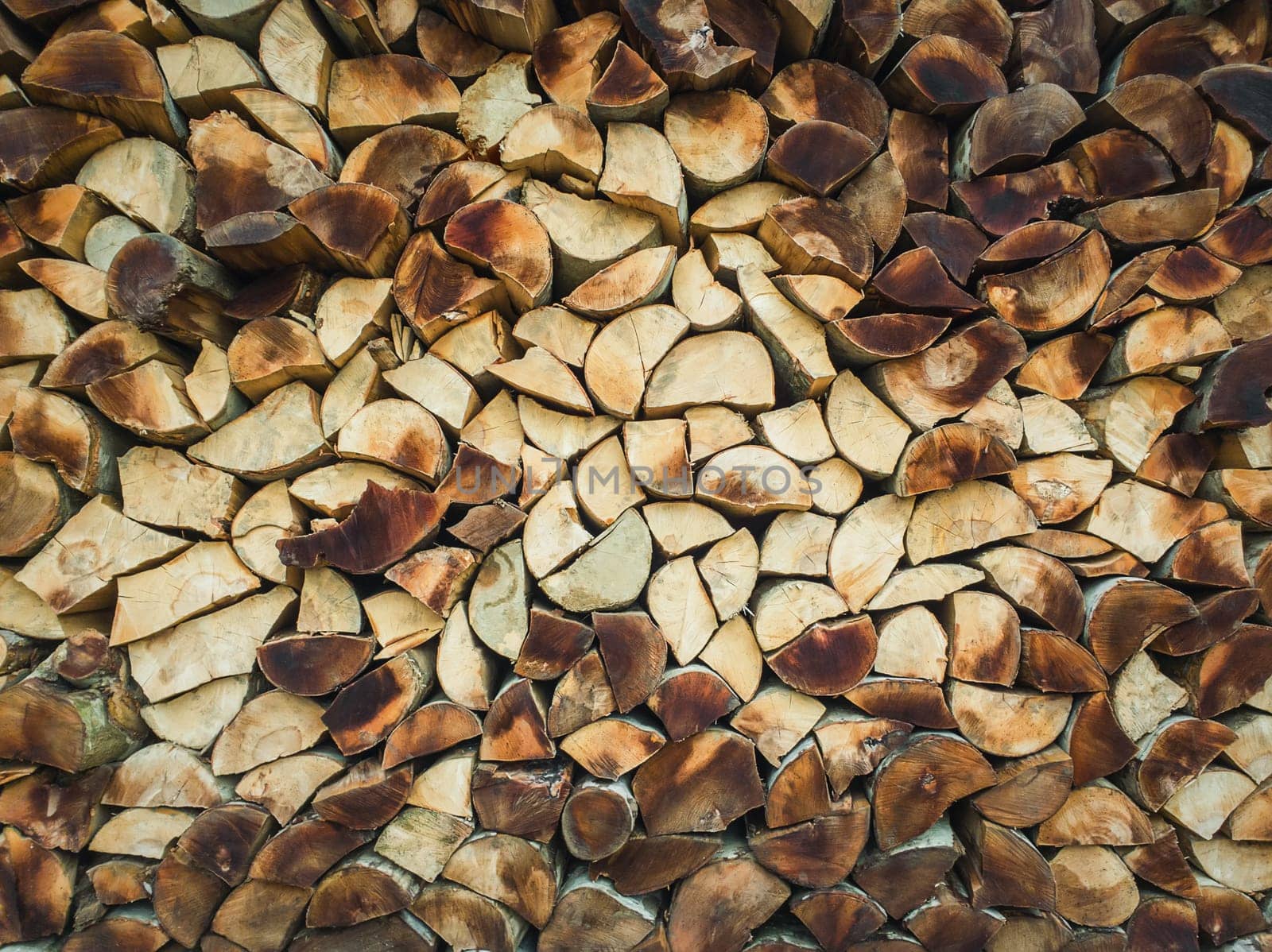 Closeup pattern of a stack of split logs, old dusty firewood. Pile texture of dry chopped wood. Winter fuel for stove heating.