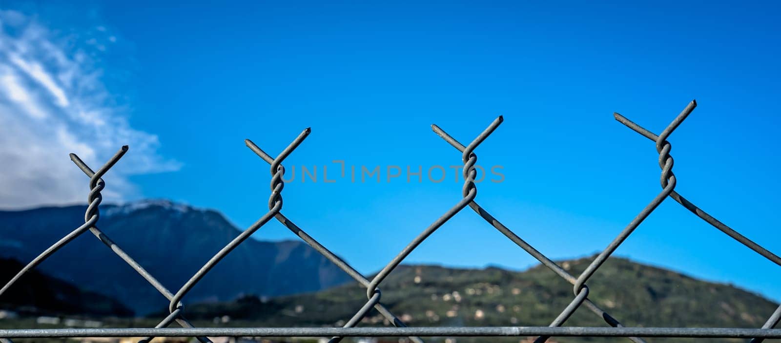 Detail of a wired metal mesh fence surrounding property in Greece