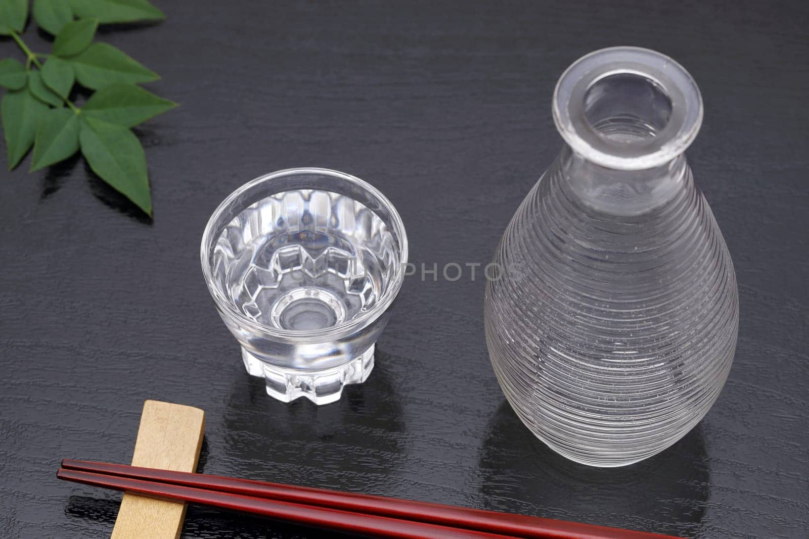 Japanese sake in transparent glass cup and jar on black background
