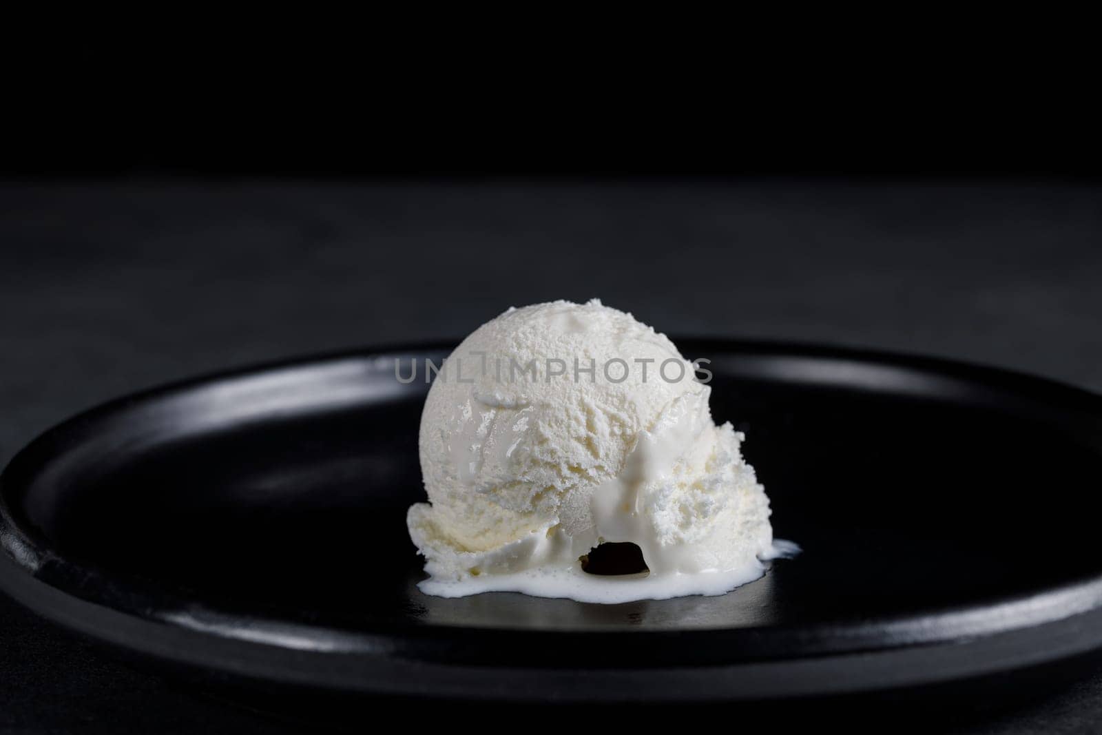 White cream ball on a black ceramic dish on a dark background