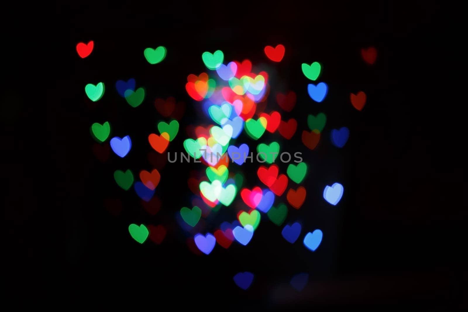Hearts form bokeh. Multicolored blurred hearts on a black background.