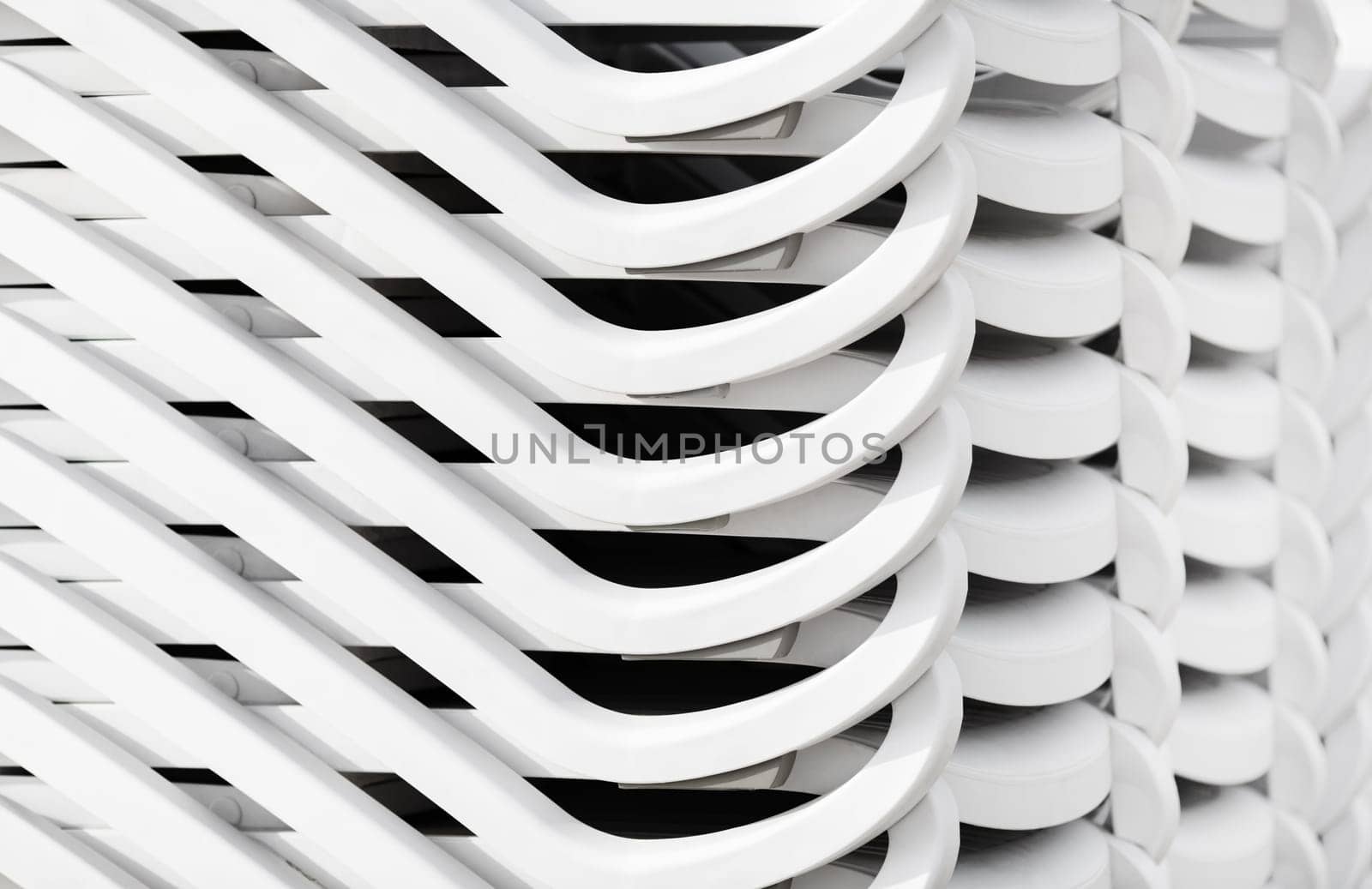 Stacked white plastic beach loungers. Abstract background.